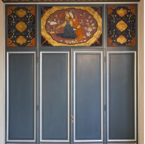 Porta chiusa dell'ingresso all'atrio con sopra una decorazione raffigurante una coppia di sposi